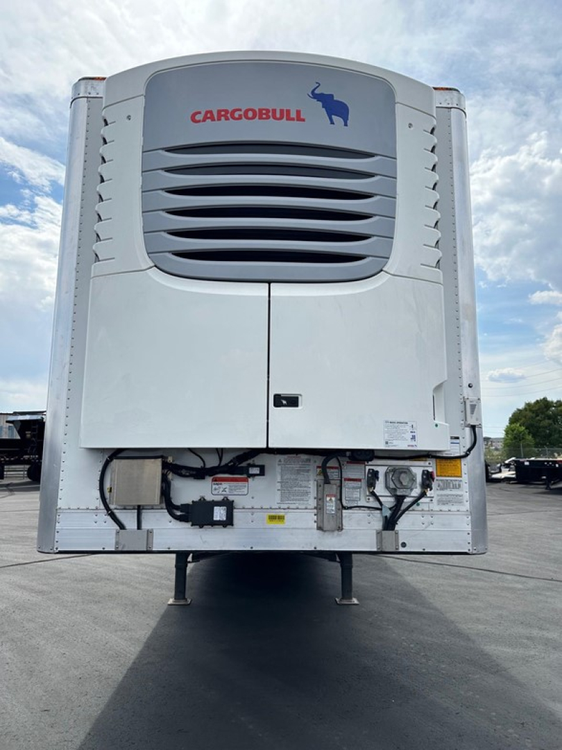 Rear view of a Cargobull utility trailer refrigeration unit showing vents, cables, and labels; blue sky background.