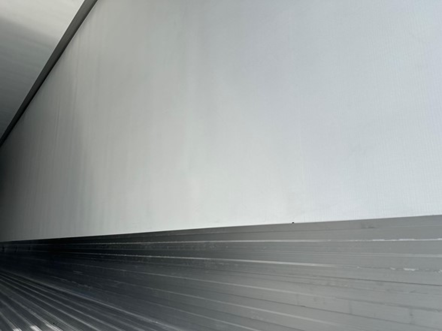 Trailer side view showing aluminum upper panel and zinc-colored corrugated lower panel, smooth seam transition, no visible branding or text.