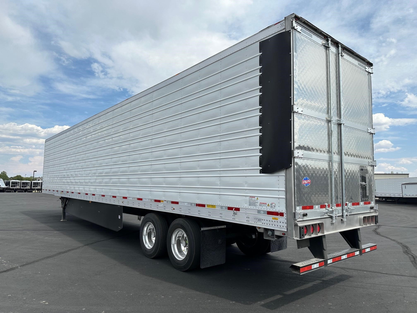 Utility Cargo trailer showing side view with tandem axles and rear double doors.