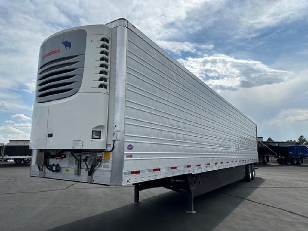 Utility Cargo Bull 625 Hybrid trailer with reefer unit at front showing cooling unit and raised hitch, side view of long silver trailer.