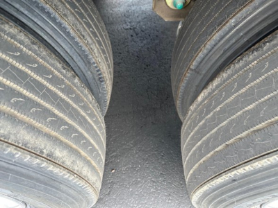 Trailer tires view showing dual wheels with tread and wheel hubs in freight yard.