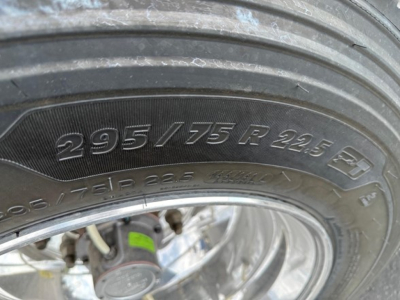 Tire sidewall showing size 295/75R22.5 on a utility cargo trailer wheel.
