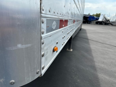 Side view of a new 2027 Utility Cargo Bull 625 Hybrid trailer showing riveted aluminum body panels, clearance lights, and reflective stripe.