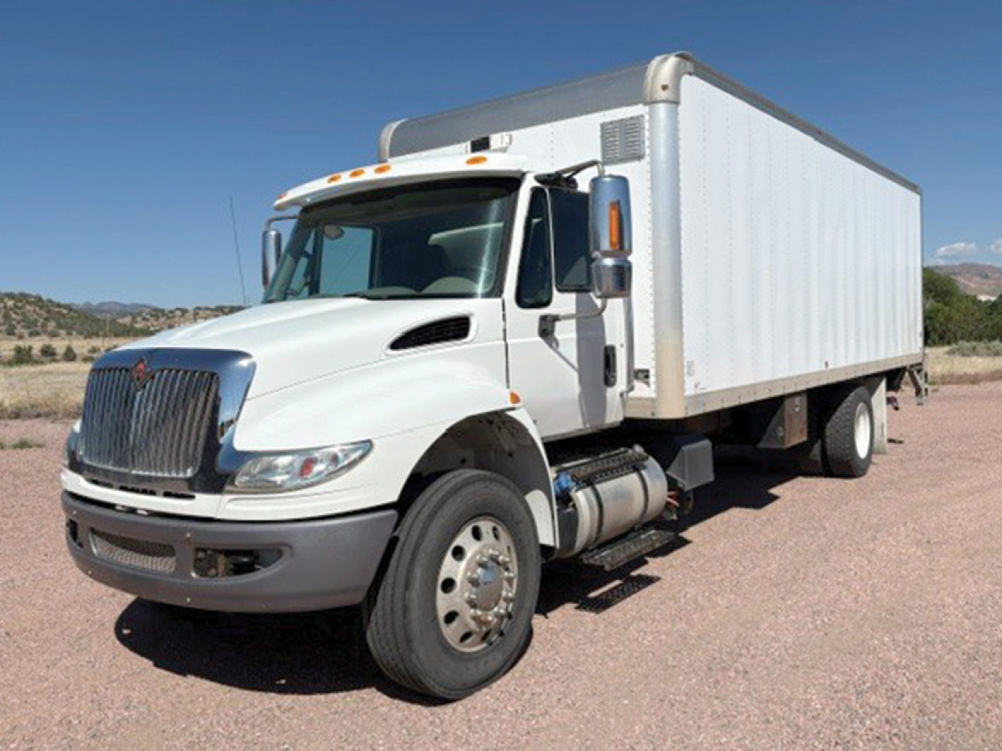 White 2019 International 4400 conventional daycab box truck front-left view showing large cargo box, dual rear wheels, cab with chrome grille, and side mirrors.