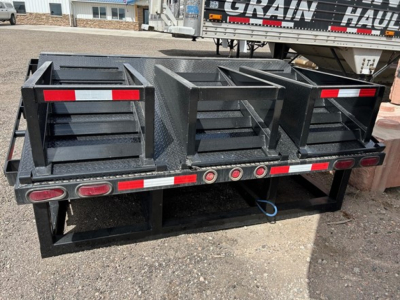 Trailer rear view showing Neville Beaver Tail with three flip ramps and stake pockets; black metal with red taillights and reflective tape along the edge.