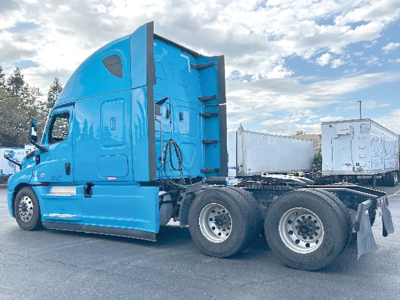 Freightliner Cascadia126 sleeper tractor truck side view with blue cab and attached trailerless chassis.
