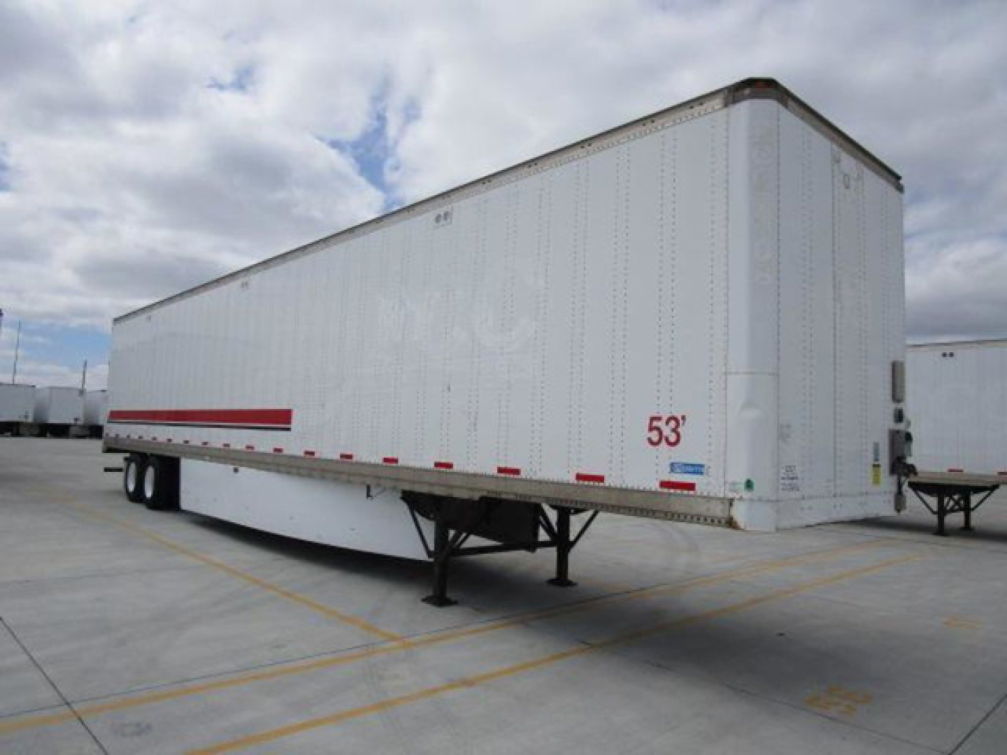 Stoughton van trailer showing side and front, white exterior, red reflective stripe, 53' length, trailer undercarriage with dual rear axles visible.