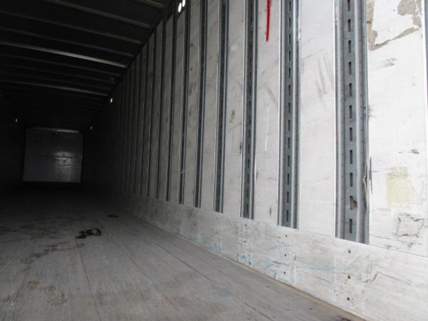 Interior of a Stoughton van trailer with metal side wall studs and wooden floor, long narrow cargo area in view.