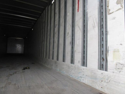 Interior of a Stoughton van trailer with metal side wall studs and wooden floor, long narrow cargo area in view.