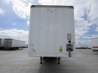Rear view of a white Stoughton trailer van with rear access door, electrical box, and support legs. Visible. stickers and labels on door.