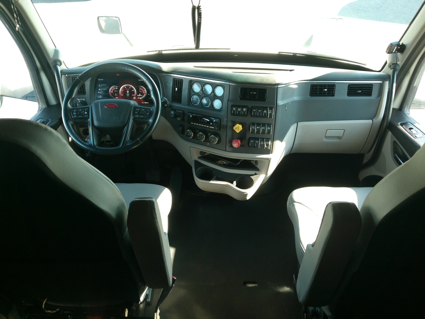 Peterbilt 579 cab interior showing steering wheel and dashboard with controls and gauges.