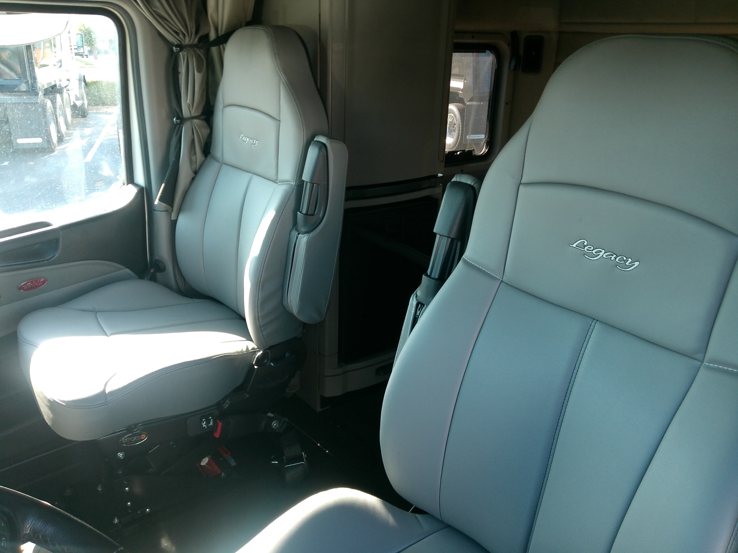 Peterbilt 579 cab interior showing light gray Legacy seats and driver area from side angle.