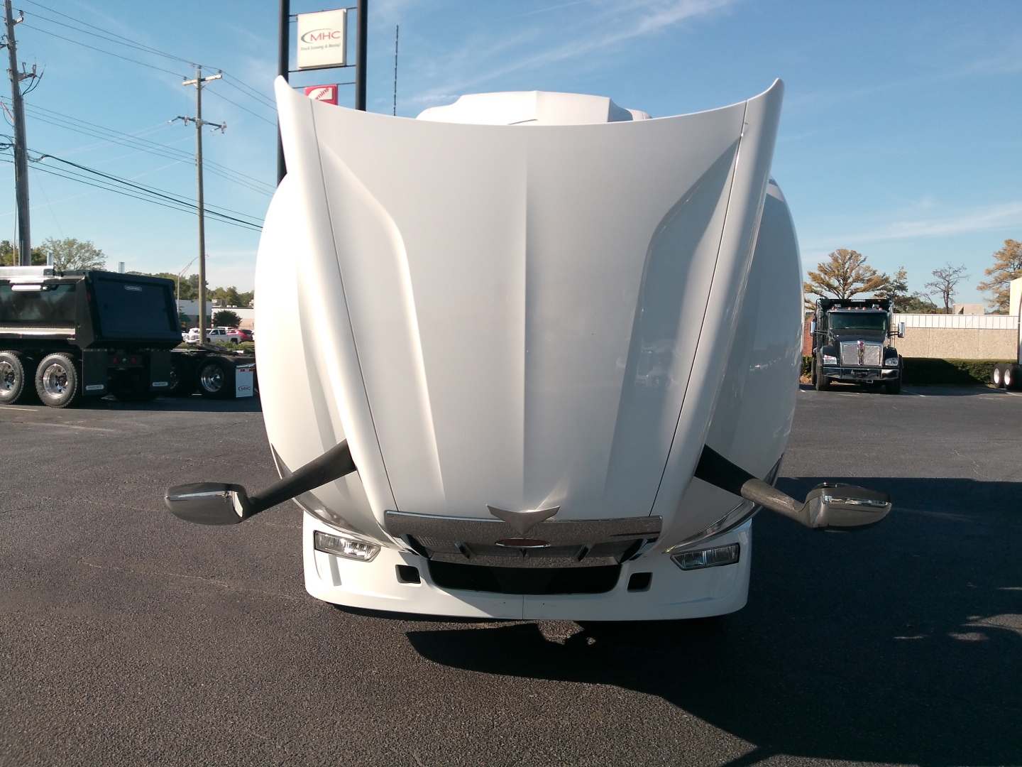 Peterbilt 579 front view with raised hood, cab-over style, in a truck lot.