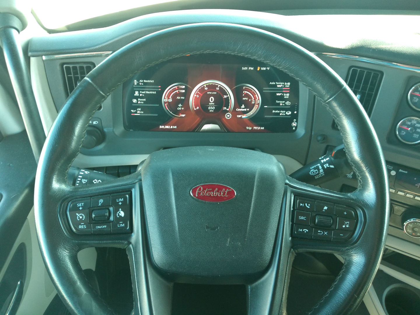 Peterbilt steering wheel in view with digital instrument cluster showing gauges and controls on both sides of the wheel in a Peterbilt 579 truck cockpit