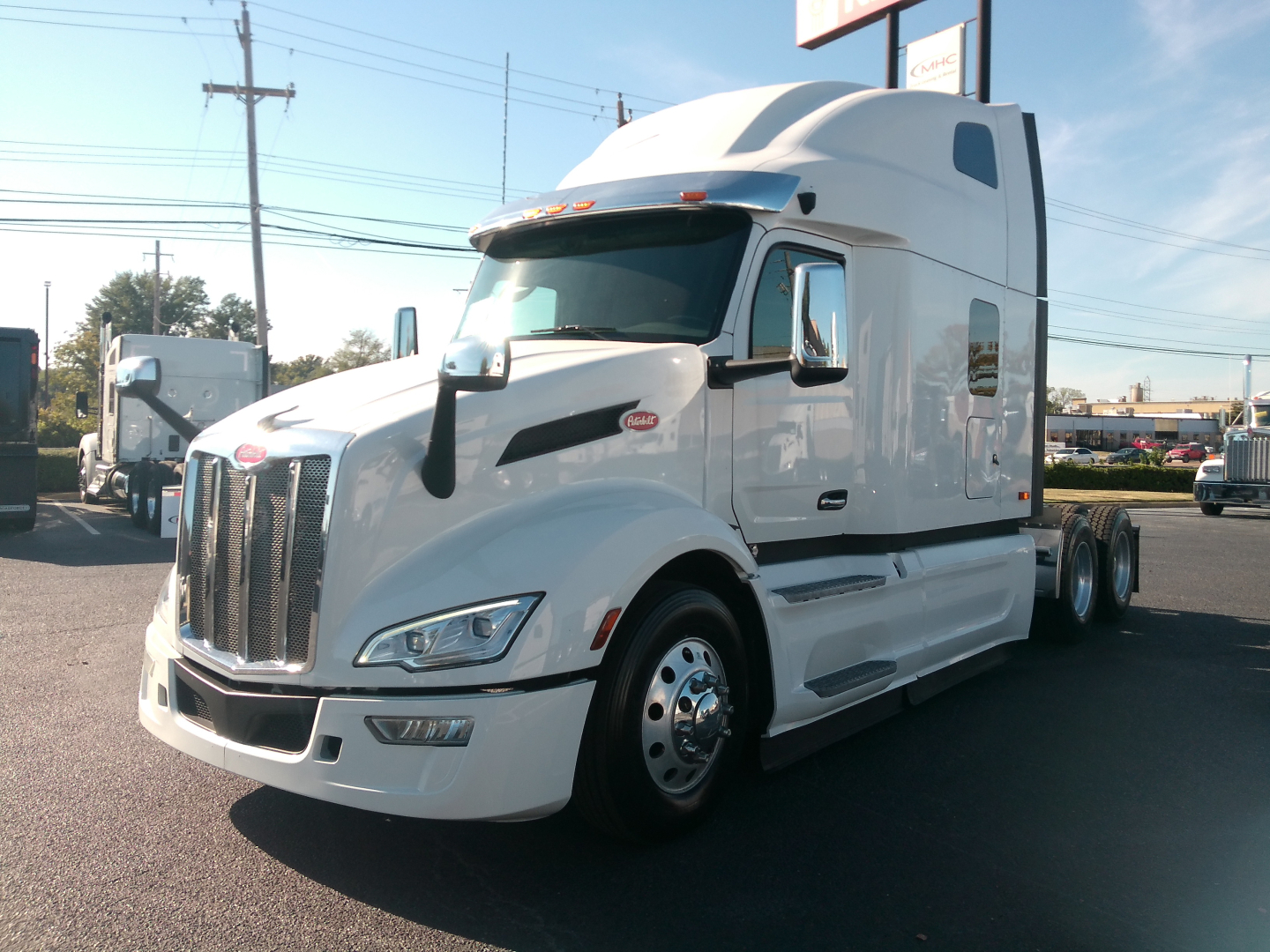 Peterbilt 579 tractor cab in white, side view showing aerodynamic sleeper, dual rear axles, chrome grille, Peterbilt emblem on hood, large side mirrors, daytime running lights.