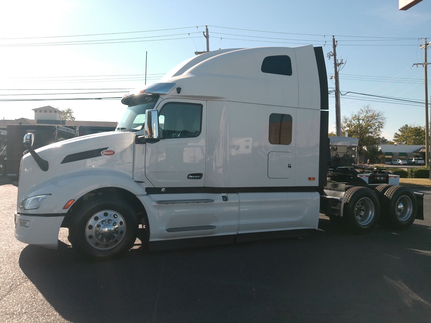 Peterbilt 579 truck in-profile view showing sleeper cab and white exterior with aerodynamic mirrors and dual rear axles.