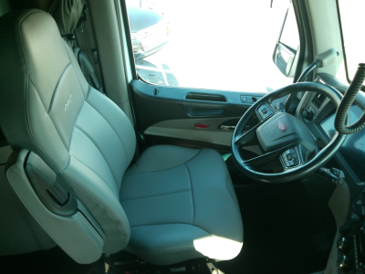 Truck cab interior showing steering wheel, gray fabric seats, dashboard, and door panels of a Peterbilt 579.