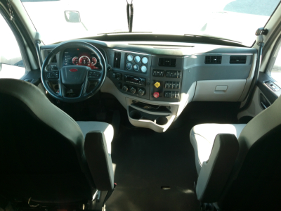 Peterbilt 579 cab interior showing steering wheel and dashboard with controls and gauges.