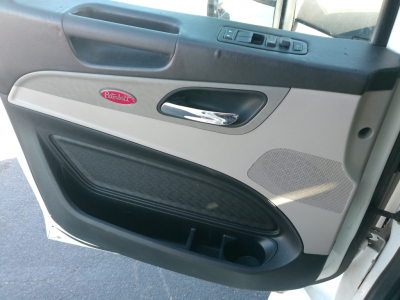 Peterbilt 579 truck interior door panel with cream and black trim, Peterbilt emblem, window controls, and storage pocket.