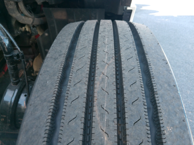 Front wheel tread of a Peterbilt 579 tractor showing worn tire with visible wear grooves and sidewall edge.