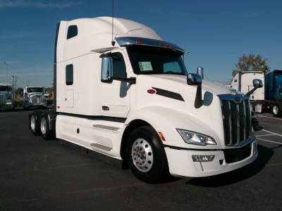 Peterbilt 579 tractor in white, side view showing sleeper cab and front grille.