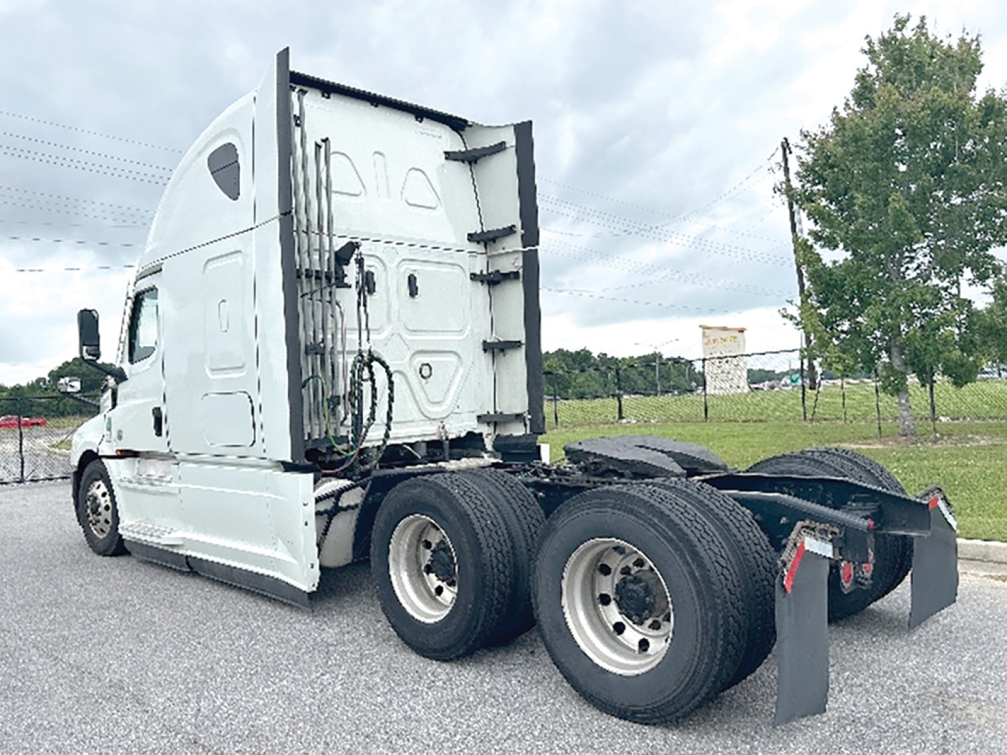 Truck rear view showing Freightliner Cascadia 126 sleeper tractor with paired dual rear wheels and exposed fifth-wheel area.