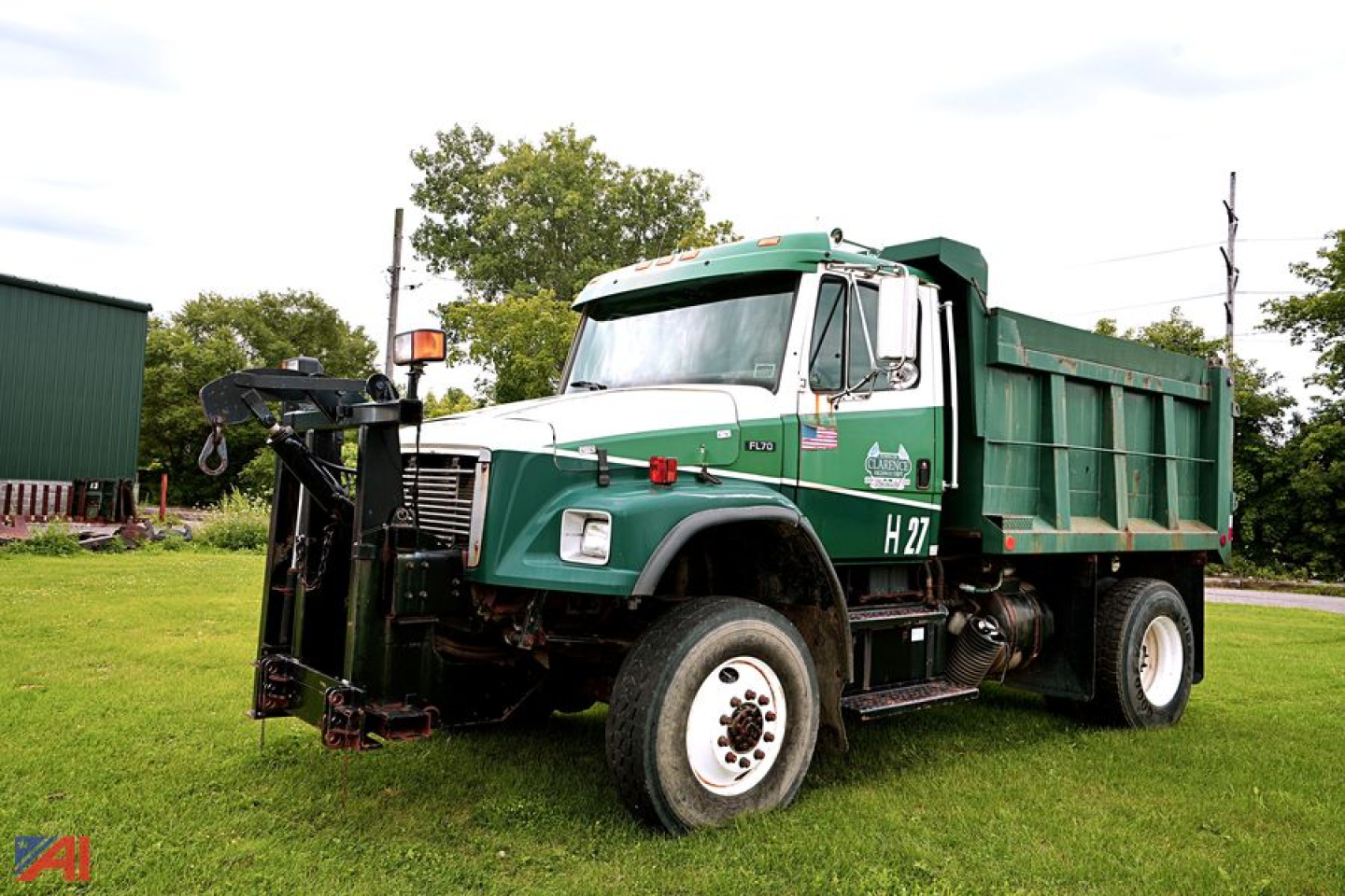 Medium-duty Freightliner F70 dump truck with plow mount showing green cab and dumping bed, H27 label on passenger door.