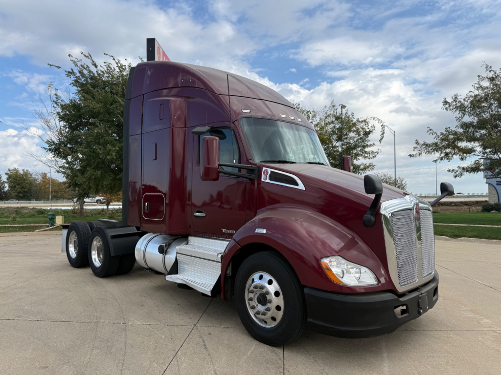 Kenworth T680 2021 conventional sleeper truck in maroon with sleeper cab, chrome mirrors, dual rear axles, front grille, and silver fuel tanks visible.