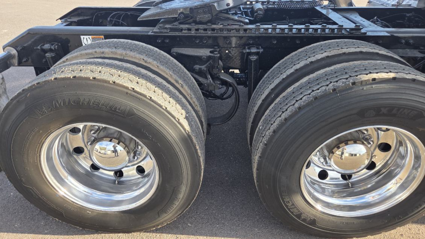 Dual rear truck wheels and drivetrain area of a 2022 Kenworth T680, showing large tires and polished chrome rims.