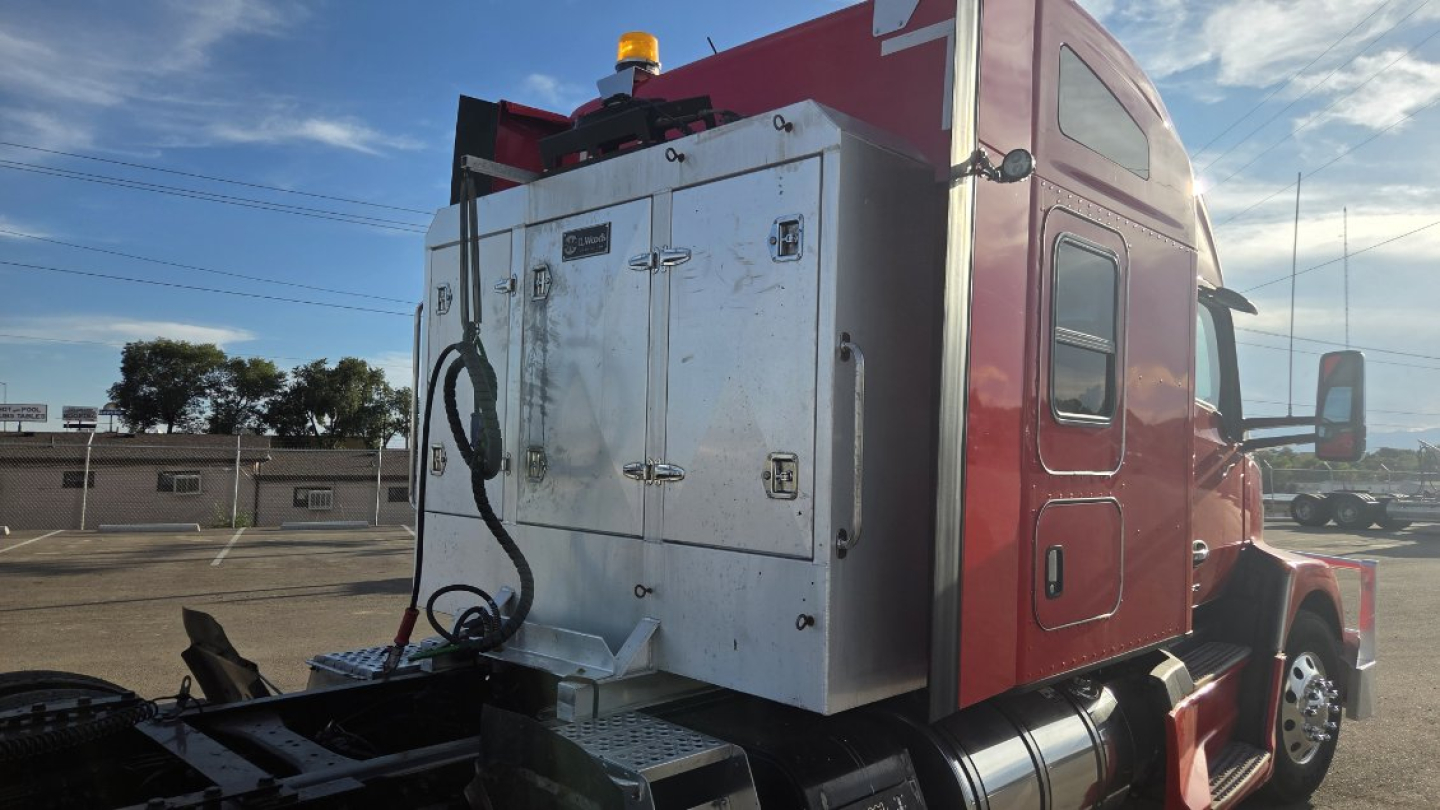 Kenworth T680 sleeper cab rear view showing metal toolbox with latches and hoses on the back of the truck.
