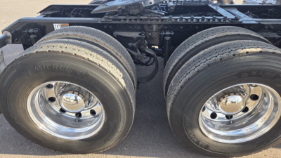 Dual rear truck wheels and drivetrain area of a 2022 Kenworth T680, showing large tires and polished chrome rims.