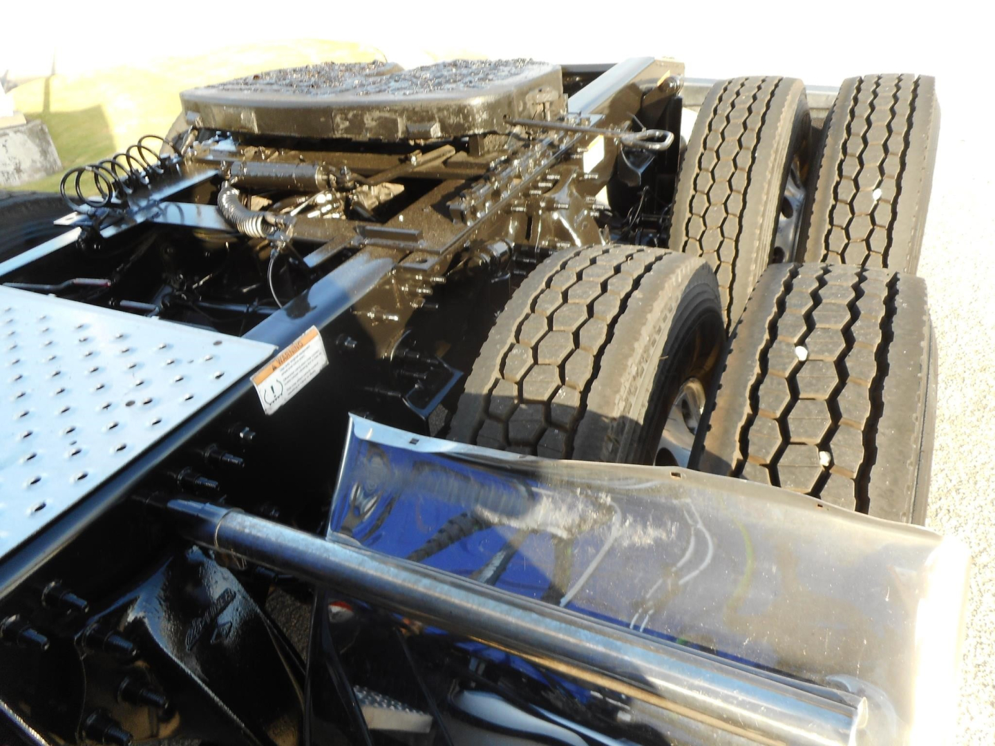 Tractor-trailer rear chassis showing dual rear axles, tires, and frame components.