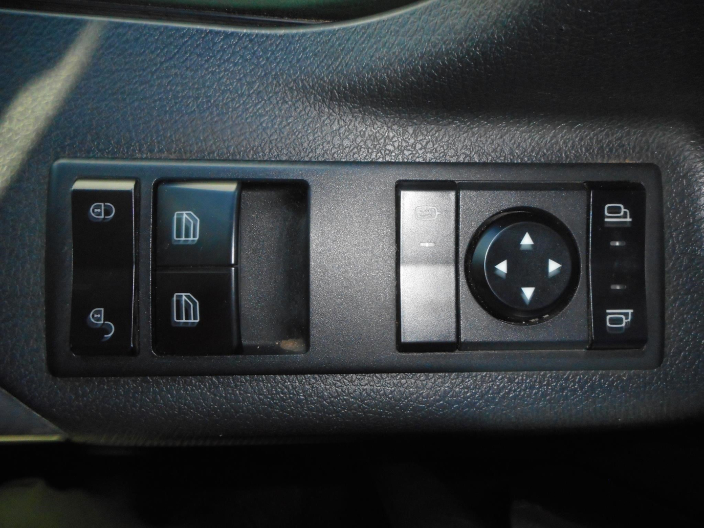 Truck interior control panel showing window and mirror adjustment buttons and a circular joystick control.