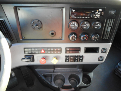 Dashboard panel of a Freightliner Cascadia 126 showing switches, gauges, and cup holders.