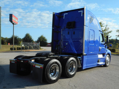 Truck cab and rear wheels of a blue Freightliner Cascadia 126 sleeper tractor from the passenger side rear angle, empty fifth-wheel area visible.