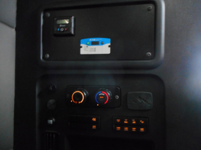Dashboard panel of truck interior with control knobs and a mounted sticker. Visible text includes a blue-and-white sticker and various unlabeled buttons.