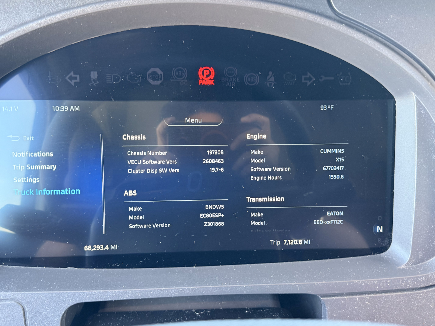 Dashboard screen of a Kenworth T680 showing chassis and engine information: Chassis Number 197308, Engine Make CUMMINS, Model X15, Software Version 67770247, ABS Make BNWDS, Model EBS, Transmission Make EATON, Trip 7128.0 MI.