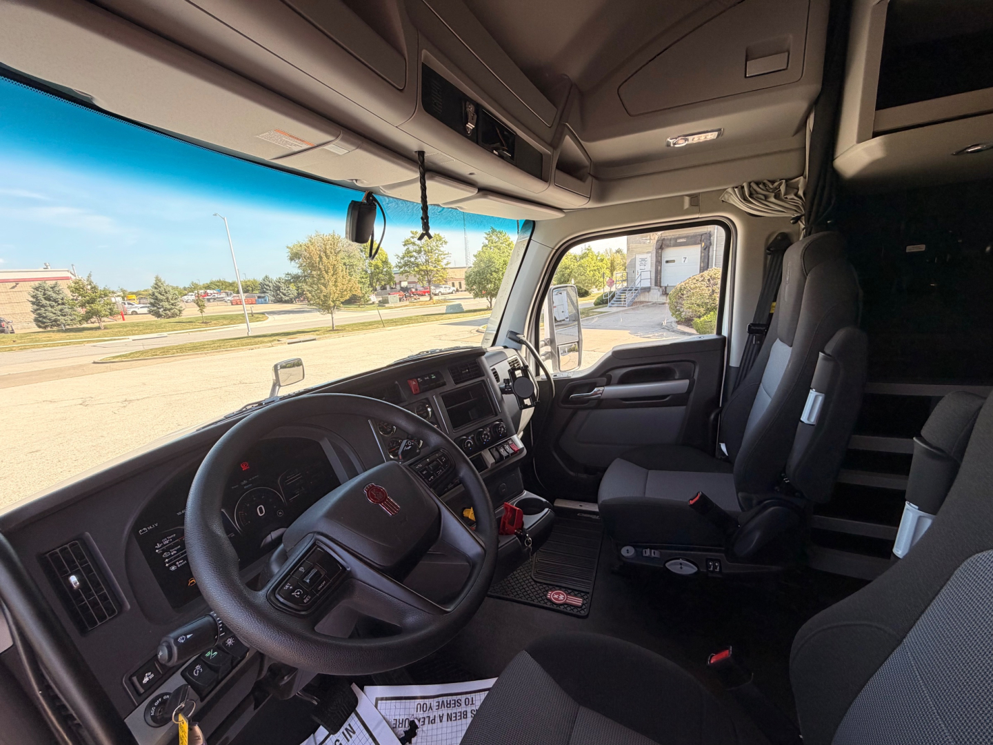 Kenworth T680 truck interior showing steering wheel dashboard and driver seat in cab with control panels.