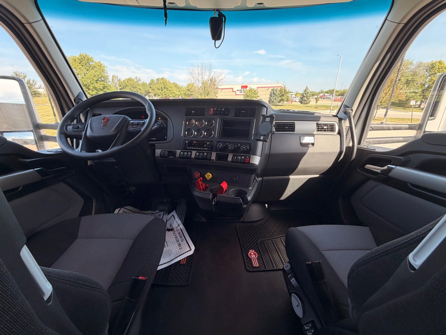 Kenworth T680 truck interior dash view with steering wheel, center console, and driver/passenger seats.