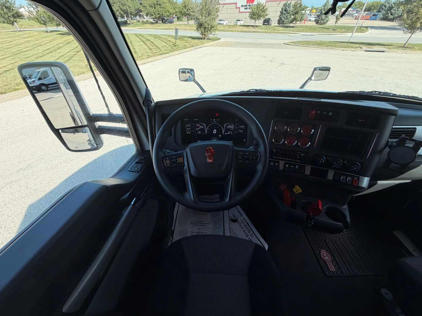 Kenworth T680 truck interior dashboard view from driver seat showing steering wheel, instrument cluster, and center console.