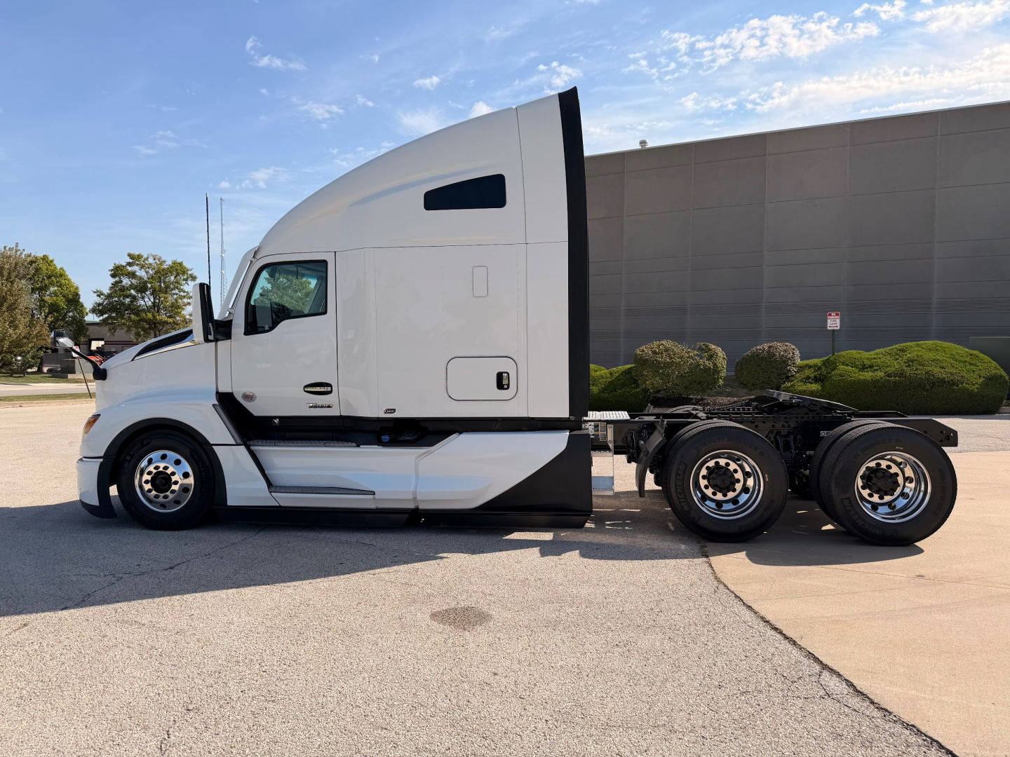 Kenworth T680 tractor side profile with sleeper cab, front wheels visible, white exterior. No visible branding text legible in image.