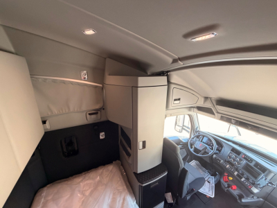 Kenworth T680 cab interior showing sleeper area with storage cabinet and dashboard view.