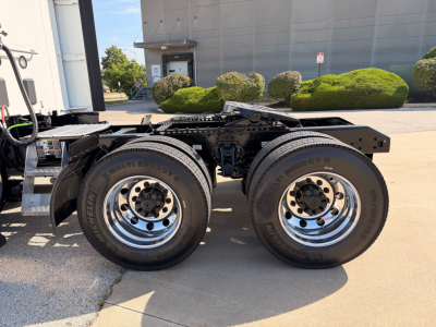 Dual rear axles with Michelin tires on a Kenworth truck chassis, chrome wheels, fifth wheel area visible, factory cab in background.