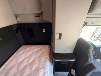 Cab and sleeper area of a Kenworth truck interior showing sleeper bed and storage cabinet.