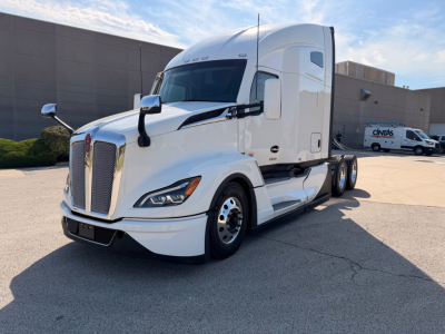 Kenworth T680 tractor trailer in white, front three-quarter view, aerodynamic hood, dual side mirrors, chrome grille, daytime running lights, two-axle rear configuration, with sleeper cab.