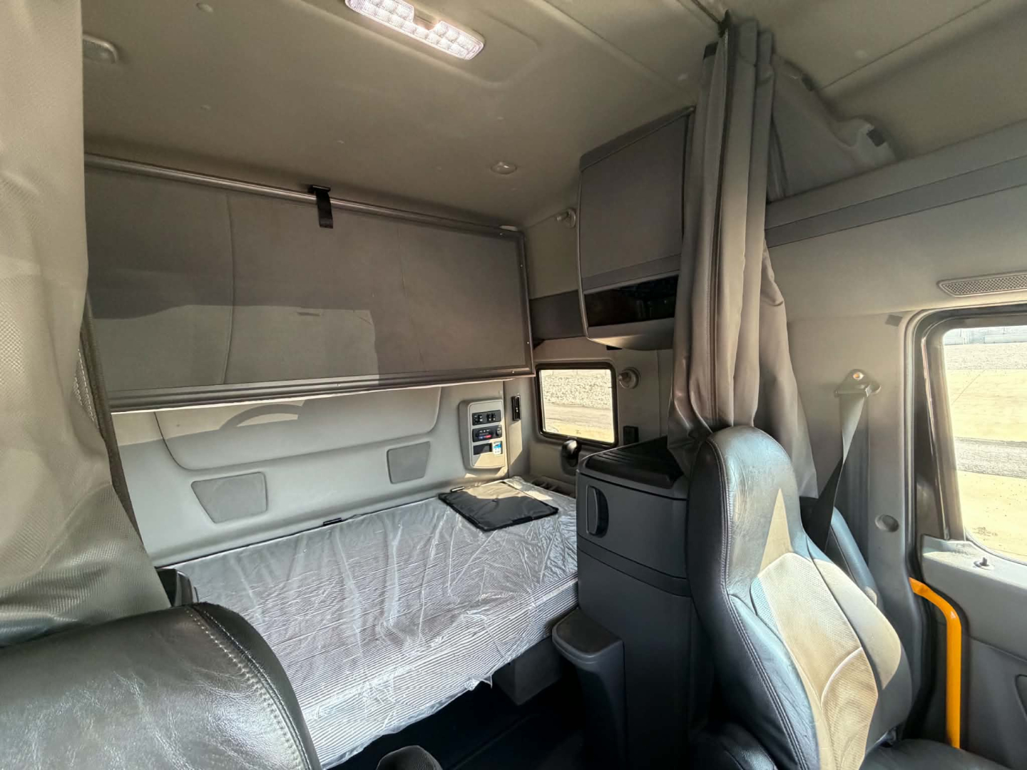 Interior of a 2023 International LT625 sleeper cab showing bunk area, overhead storage, and cab console with a small monitor.