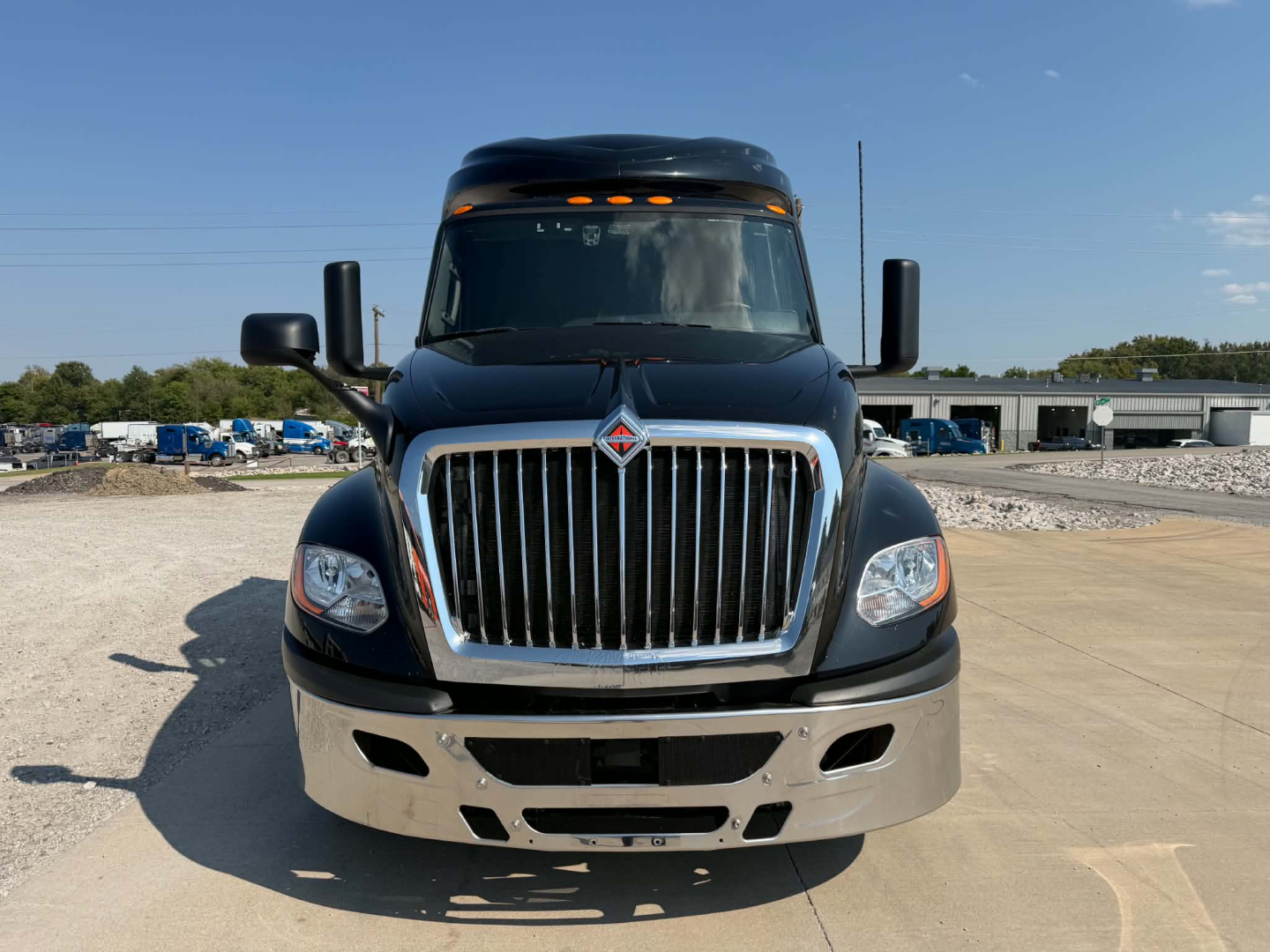 Truck front view showing International LT625 badge on grille, large chrome grille, black hood, headlights, bumper with fog lights, and side mirrors.