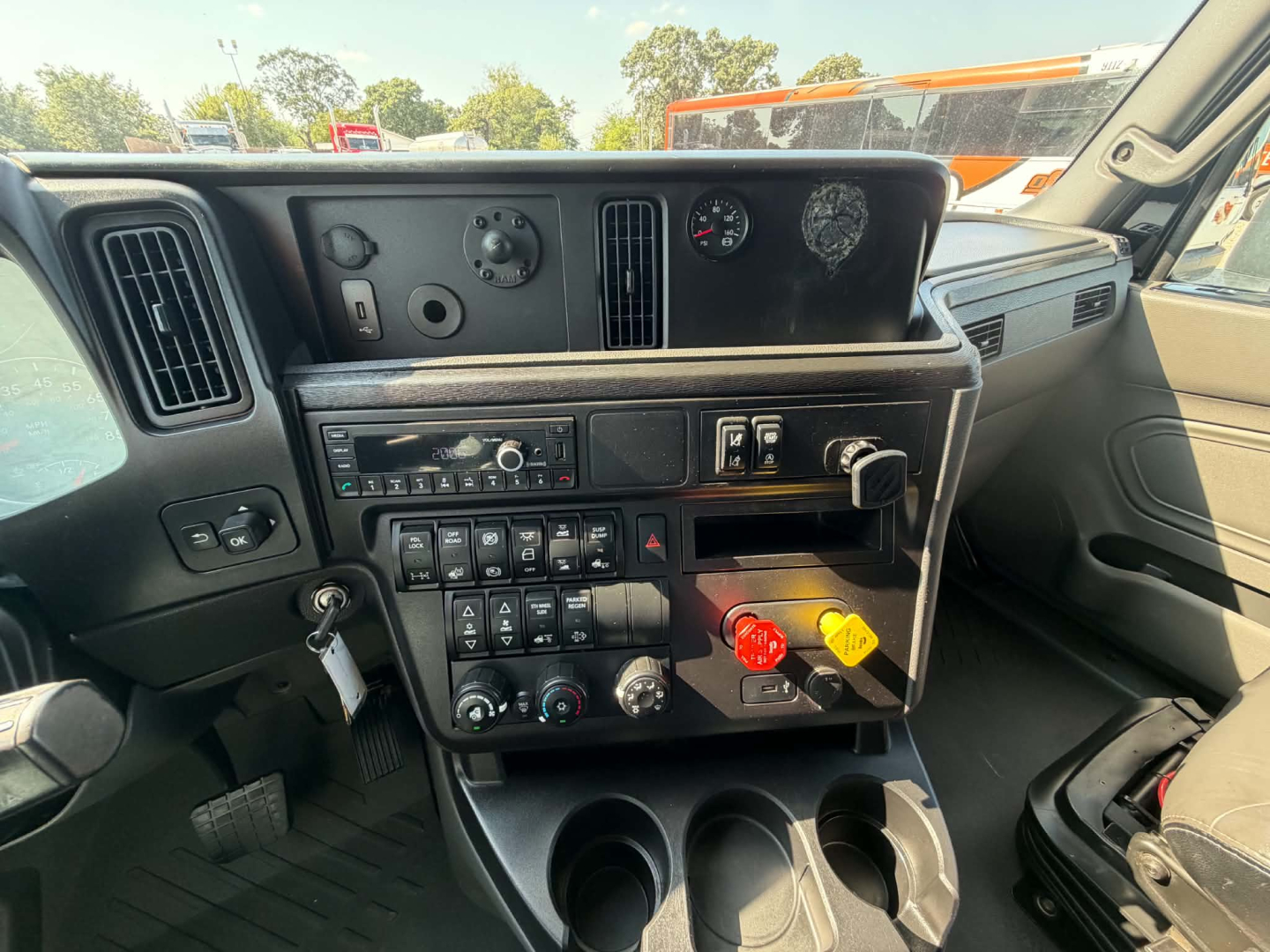 Interior dash of a 2023 International LT625 conventional sleeper showing control panel with switches, vents, gauge cluster, and cup holders.