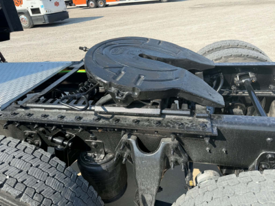 Tractor-trailer chassis area with circular locking device and fuel/air lines; portion of fifth wheel mounting and tire visible