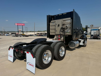 Truck rear view showing dual rear axles and sleeper cab. Visible are fuel tanks, rear mud flaps, and chassis with fifth-wheel area.